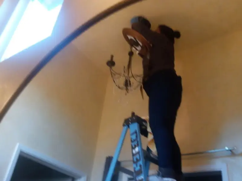 Electrician installing a chandelier in a Fort Myers residence